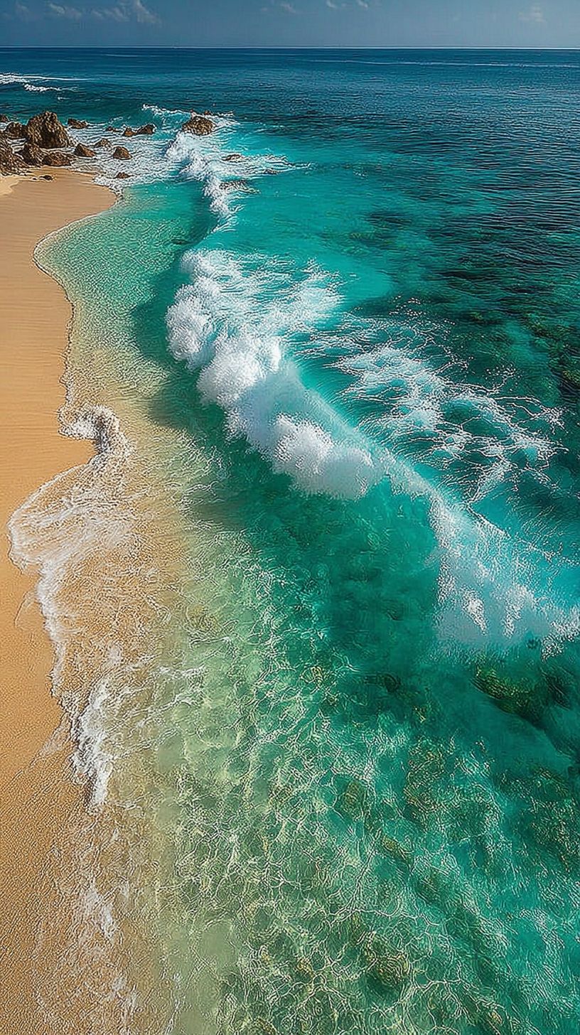 Seafoam green waves meet a pristine white beach with clear water and a minimalist shoreline
