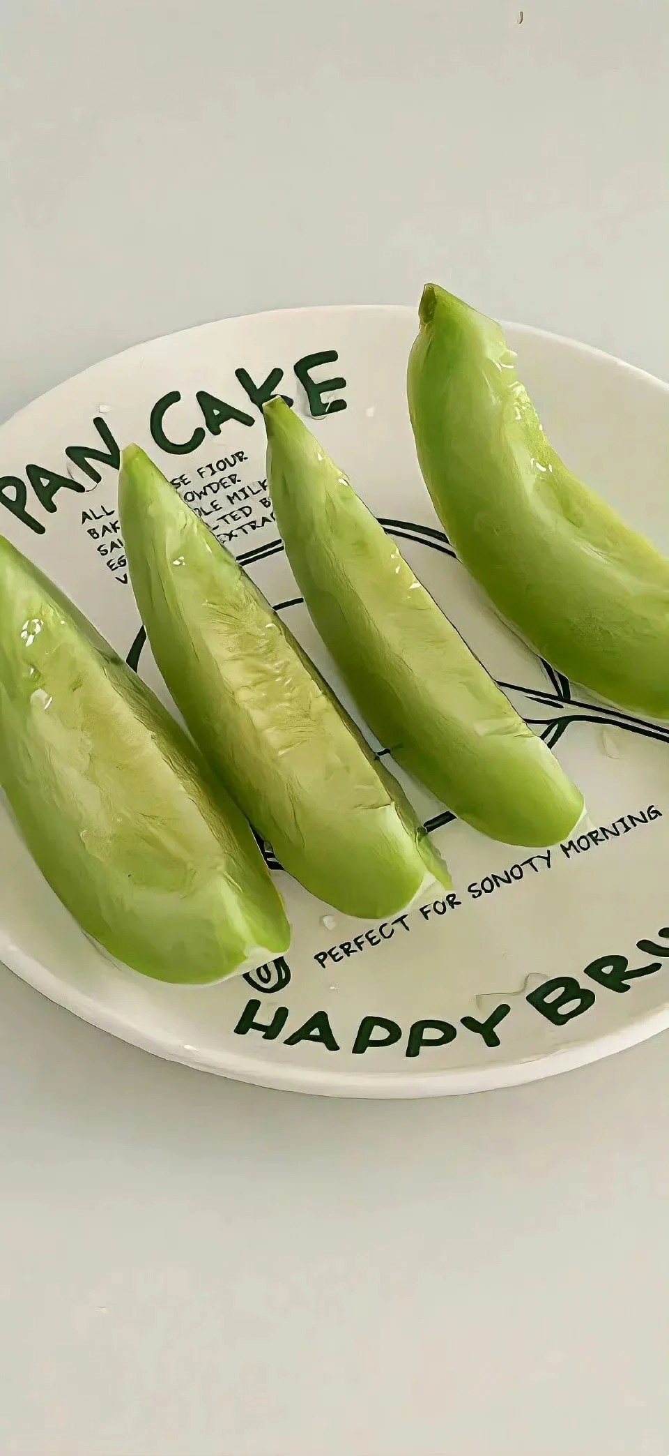 Four pieces of green melon are neatly arranged on a white plate showcasing their refreshing texture
