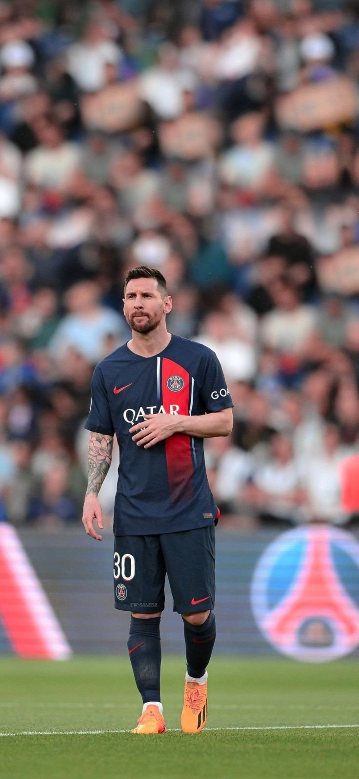 パリ・サンジェルマンの30番のユニフォームを着たサッカー選手が尊敬の意を示すために胸に手を置いてピッチに立っている