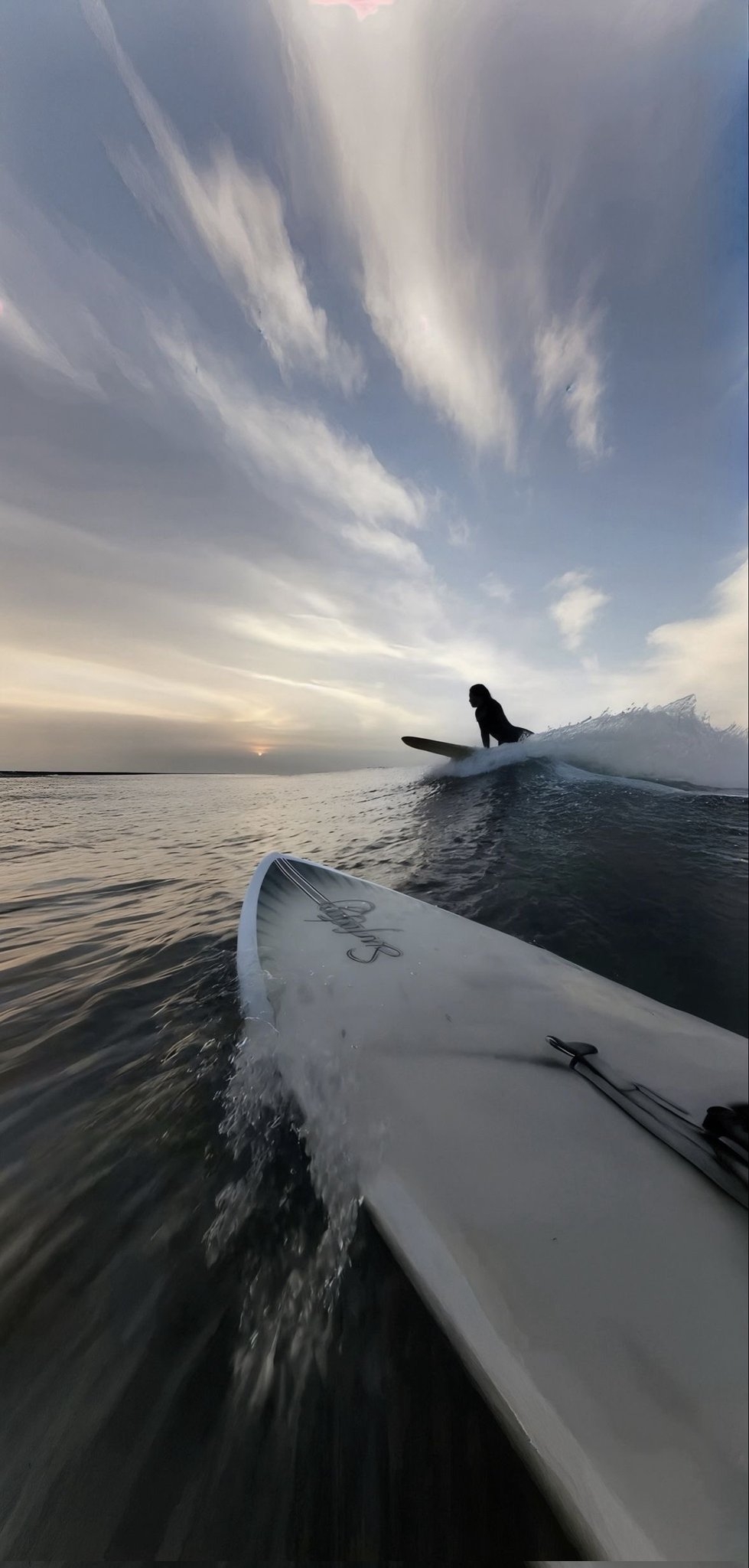La perspective de la planche de surf capture l'harmonie entre la personne et la nature dans une scène marine au crépuscule