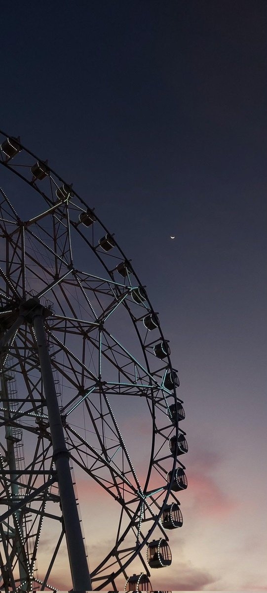 Uma fotografia de uma roda-gigante ao crepúsculo durante a hora azul captura o momento sereno entre o dia e a noite