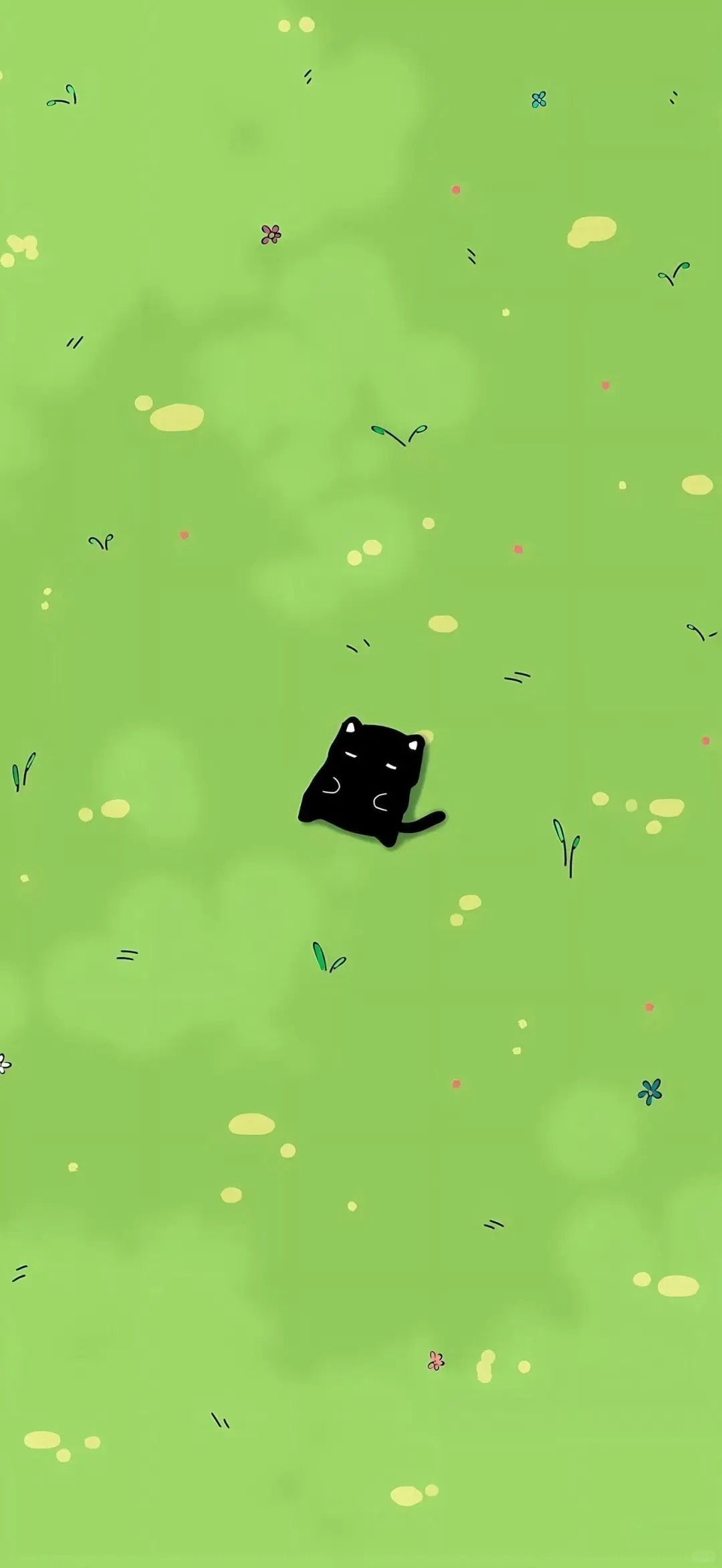 A small black cat is lazily lying on the light green grass