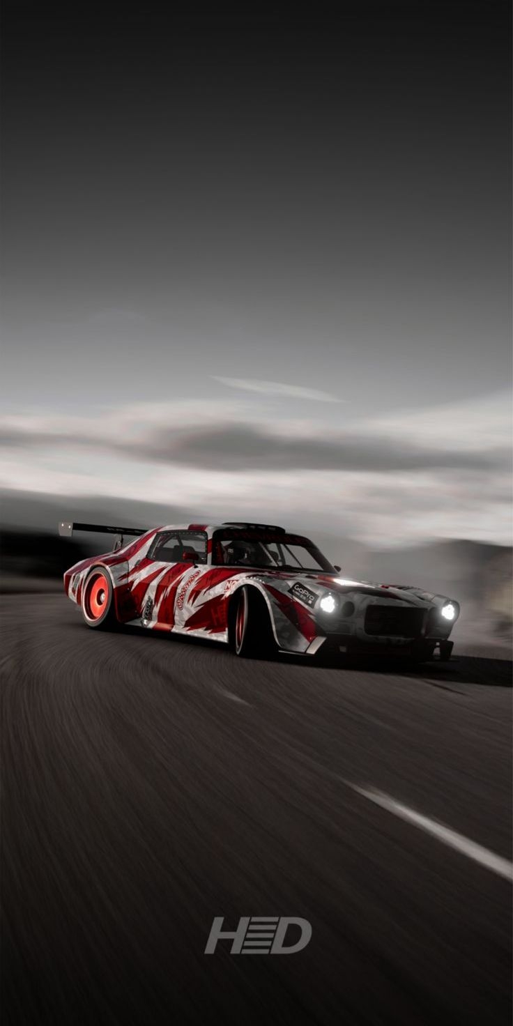 A Nissan GT-R with a wild red and white paint scheme is parked under moody overcast skies