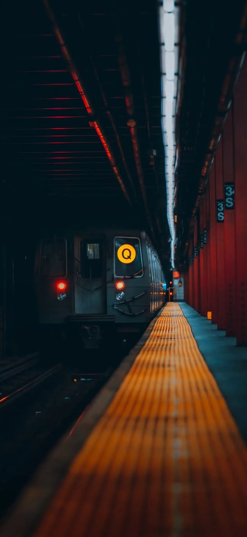 Der Q-Zug in New York fährt auf einen schwach beleuchteten Bahnsteig ein