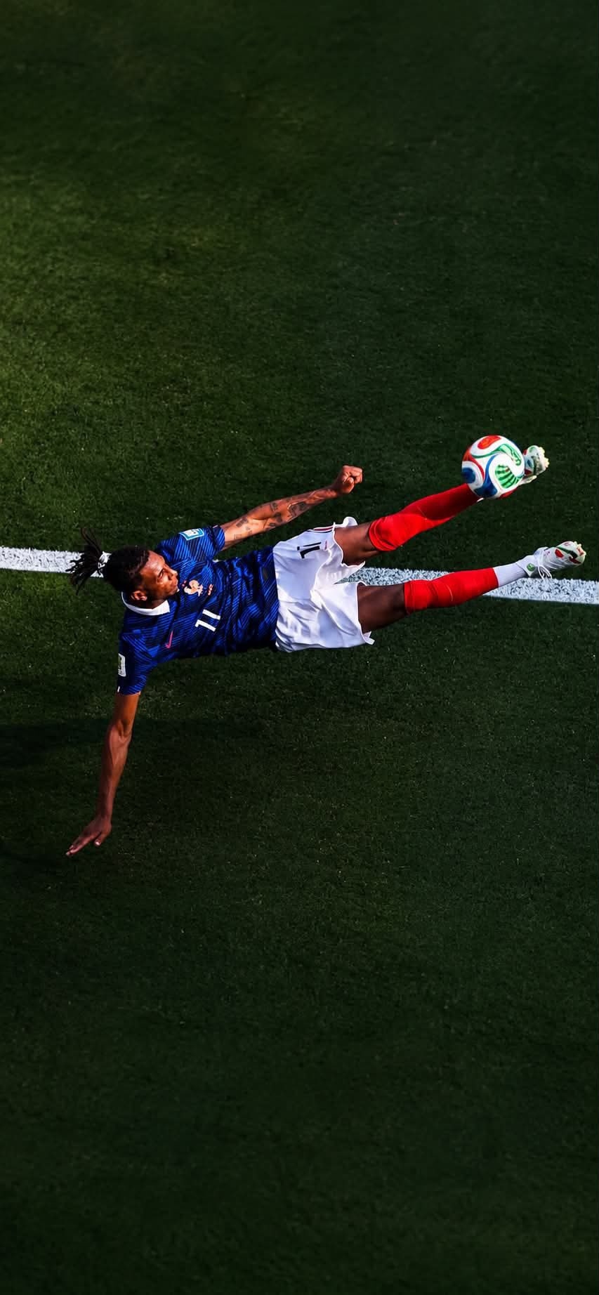 Soccer player performing an aerial bicycle kick on a lush green field, action full of tension.