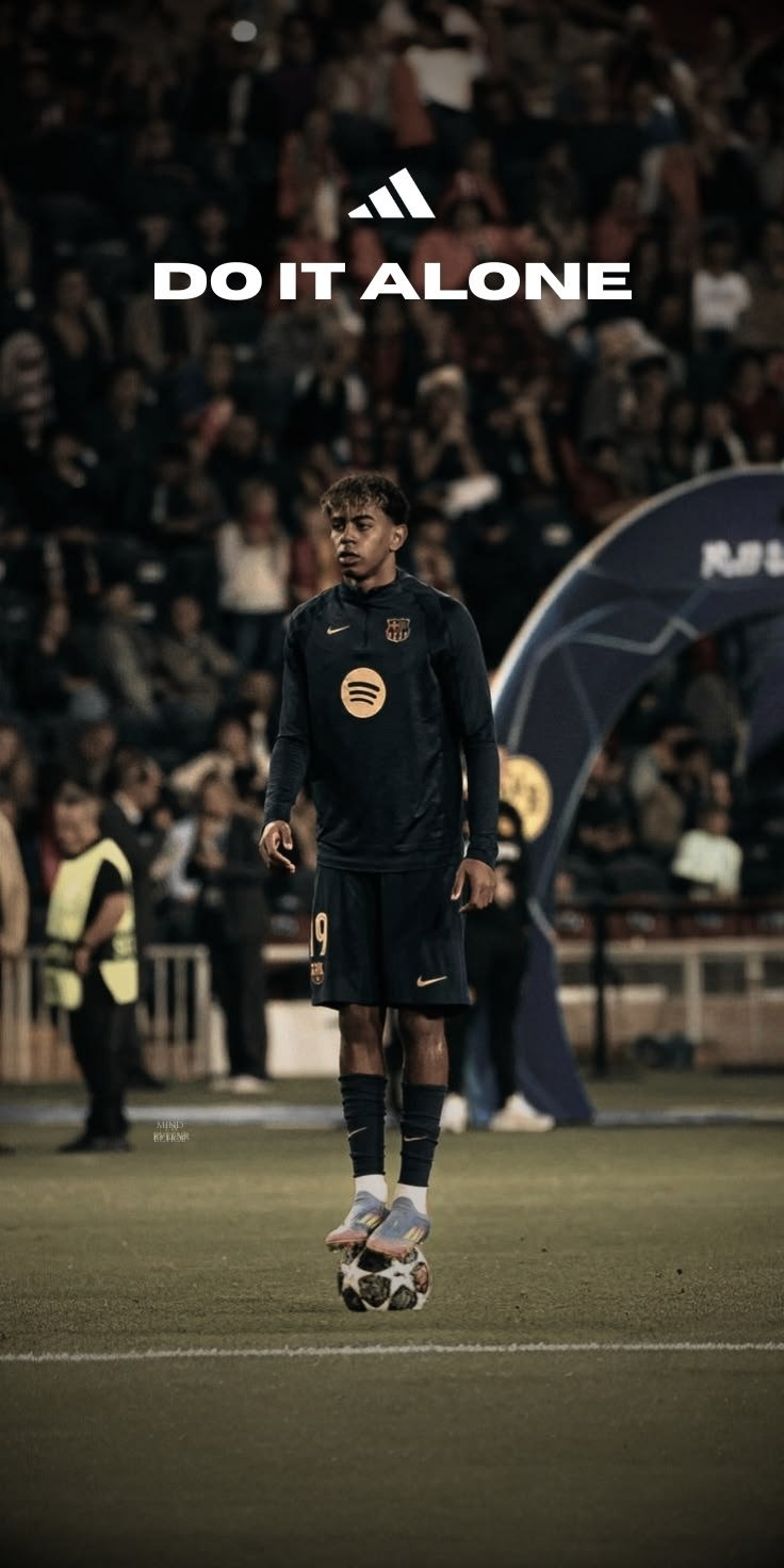 Um jogador de futebol está em pé no campo com a bola aos pés