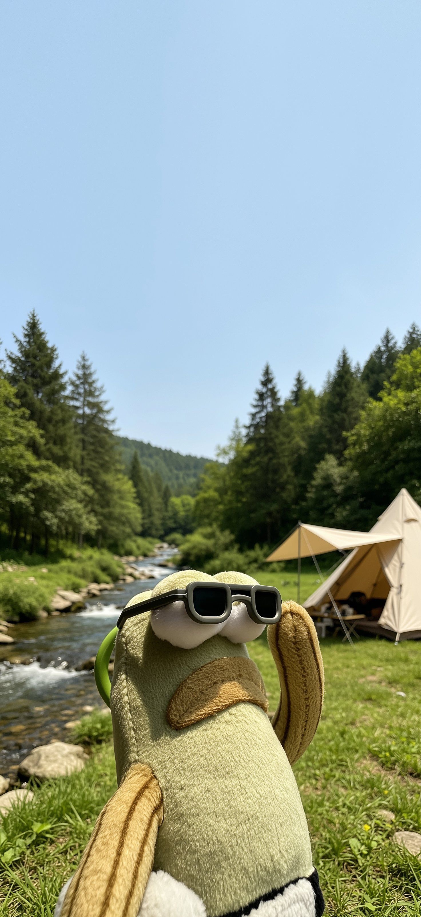 A plush toy sits on green grass by a river