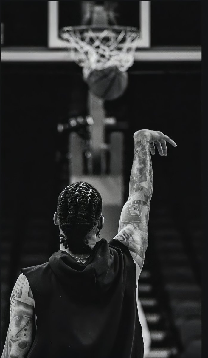 Uma foto esportiva em preto e branco capta um atleta tatuado no momento do arremesso