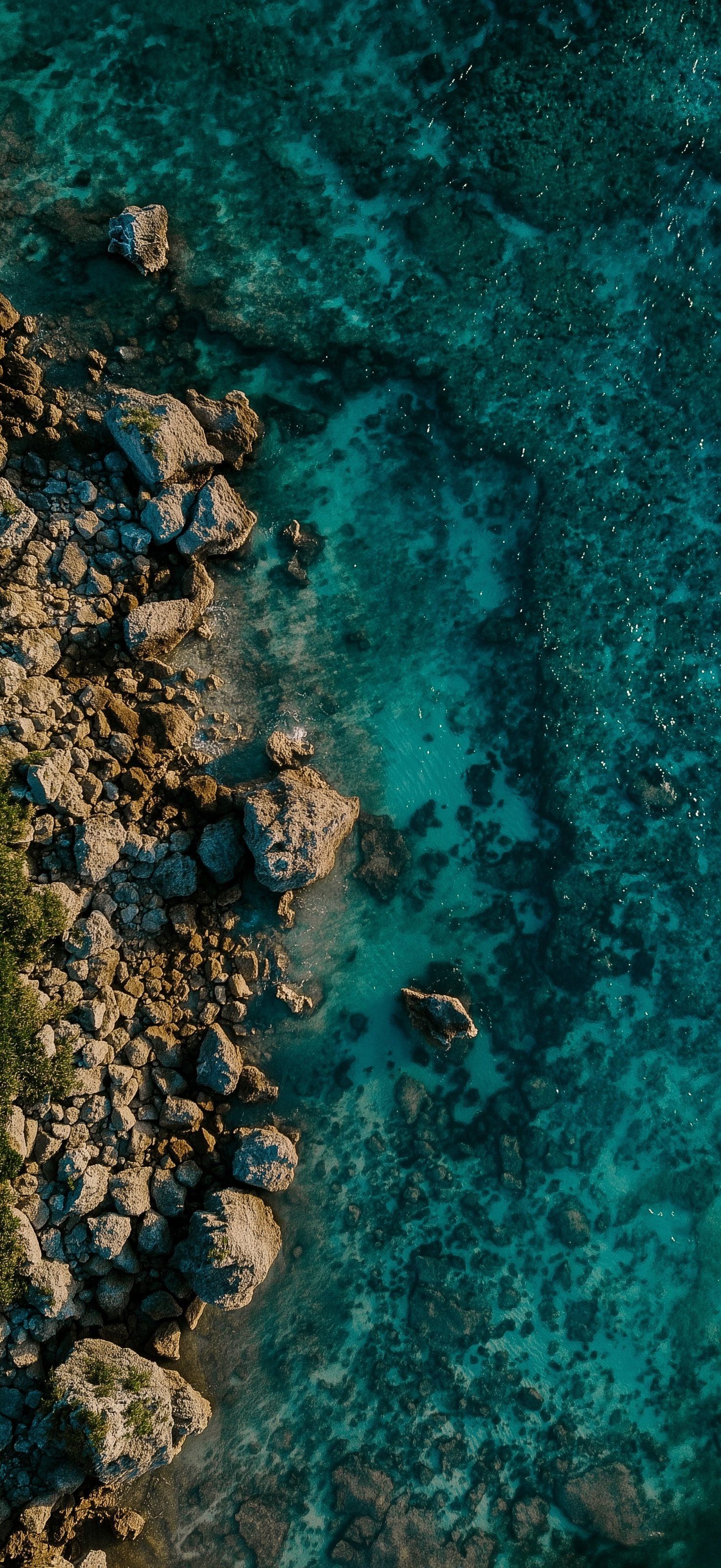 Une vue aérienne capture une côte escarpée rencontrant des eaux turquoises translucides