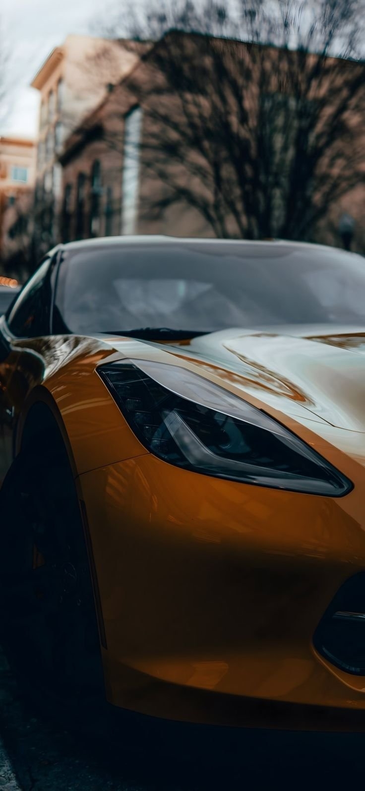 A glossy amber-orange sports car exuding dynamism and speed against a soft background