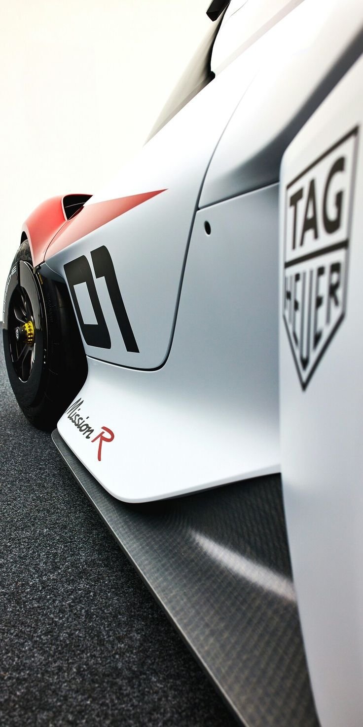 A close-up of a sleek white race car featuring bold black graphics and a TAG Heuer logo