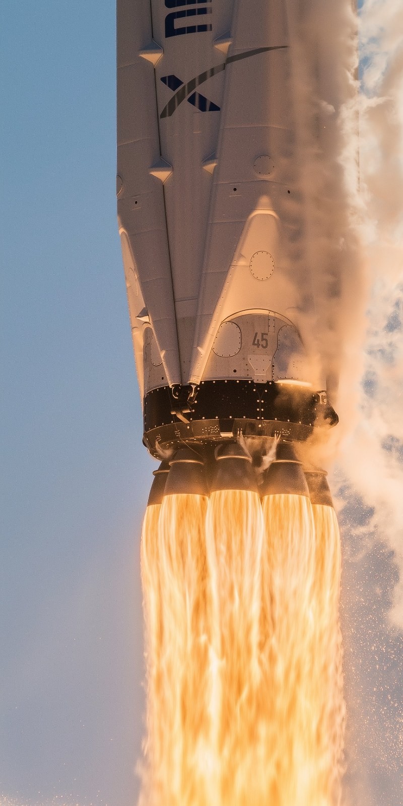 The low-angle shot of the white rocket's bottom showcases the flames and smoke from its engines