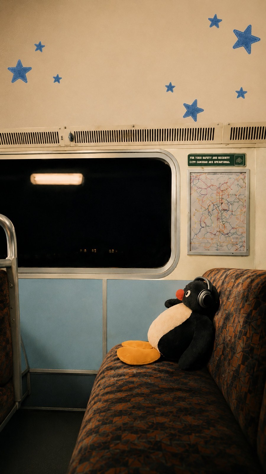 In a late-night train, a penguin plush toy quietly gazes out the window