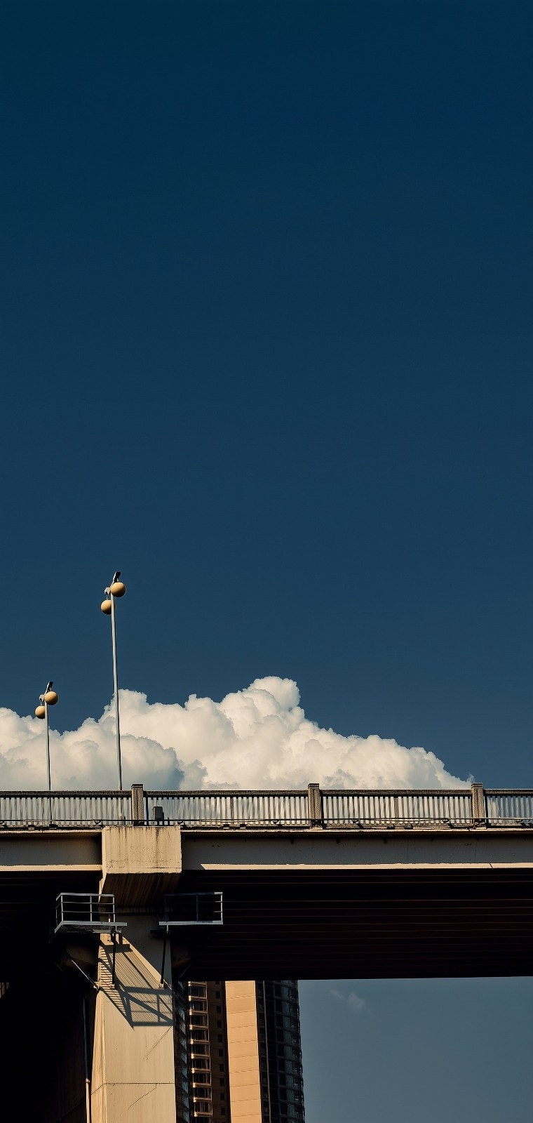 Uma ponte elevada cria contraste com superfícies brilhantes e um céu azul profundo com nuvens ao fundo