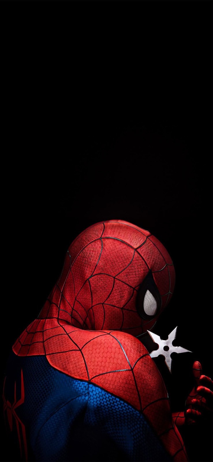 A hero in a red and blue costume stands with his back to the camera holding a dart