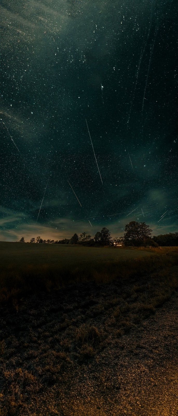 The deep blue night sky is filled with stars, with meteors streaking across and warm yellow light illuminating the scene