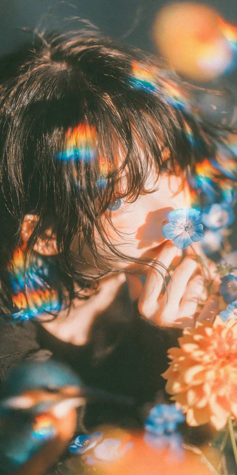 Um personagem de anime com cabelo escuro exibe uma expressão melancólica entre flores azuis e laranjas