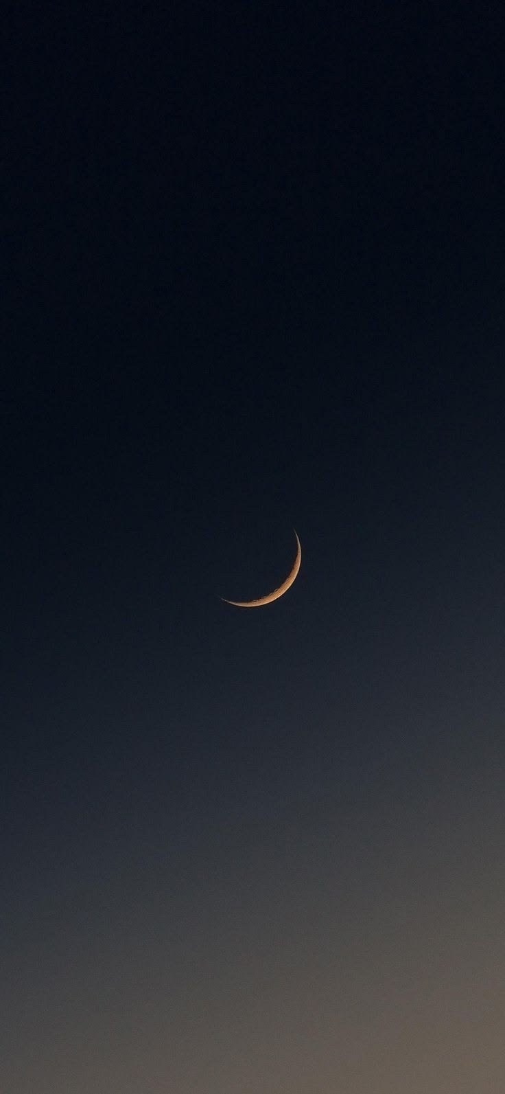 Slender crescent moon emits warm golden glow in pure gradient night sky
