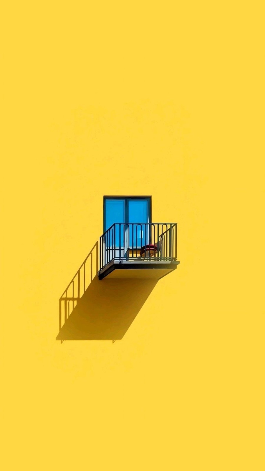 A balcony with an iron railing contrasts with the yellow wall