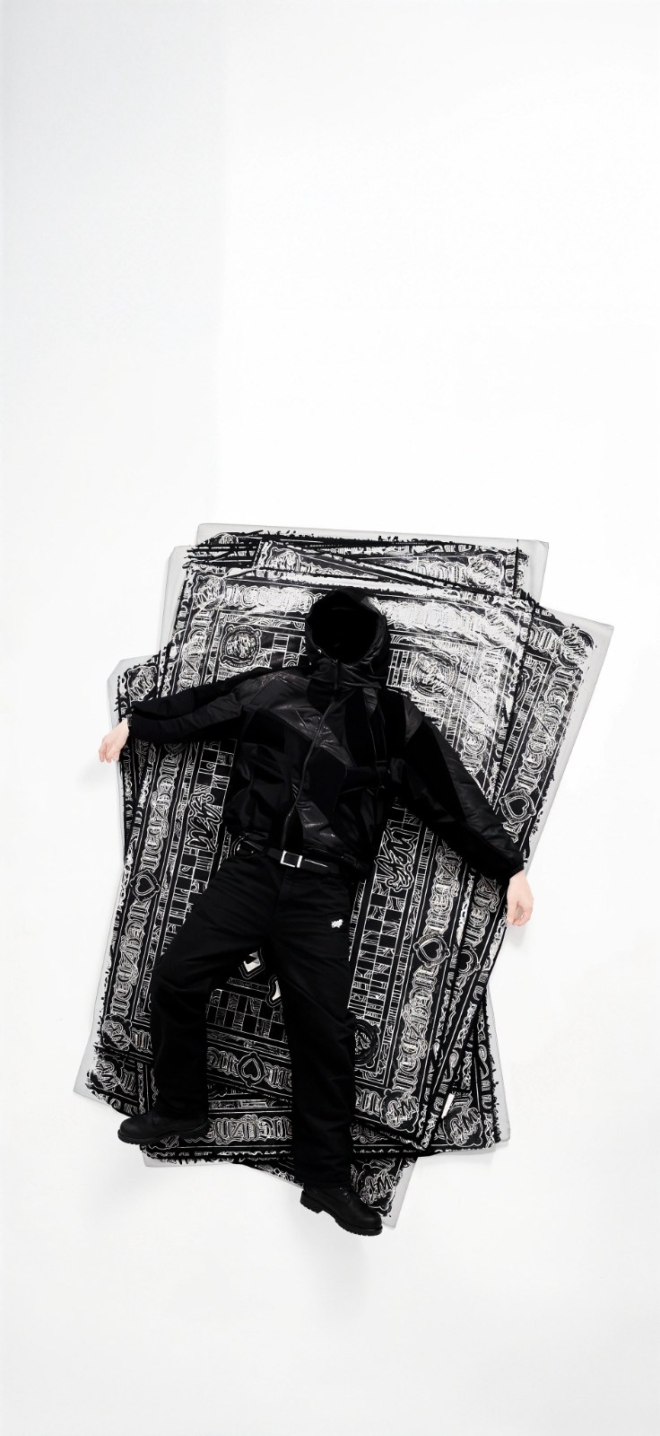 A person in black lies on their back against a white background
