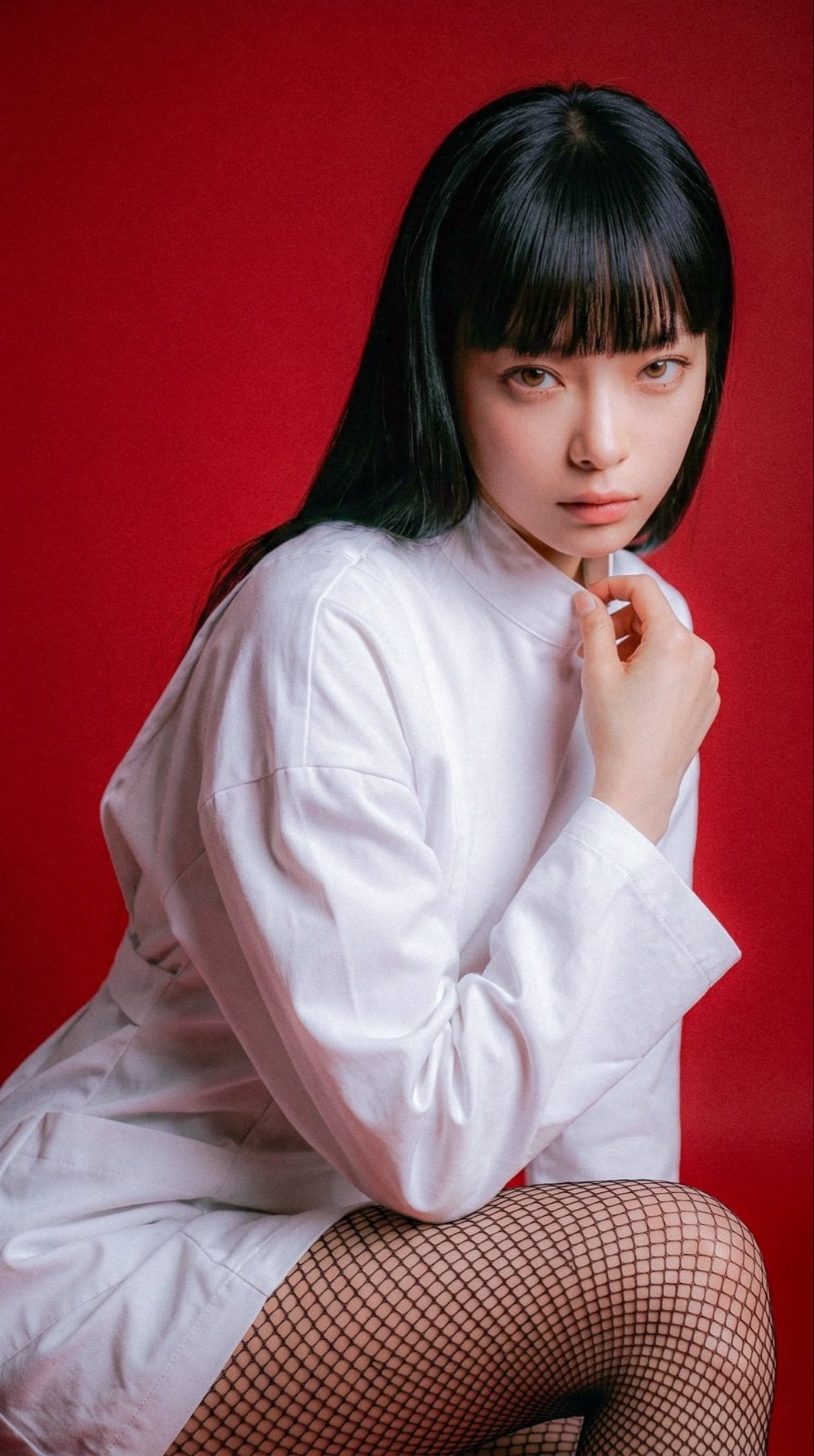 A woman in a white turtleneck and black fishnet stockings